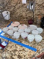 All tea cups, saucers, and dessert plates arranged on a granite countertop showing the floral pattern and quantity of each item.