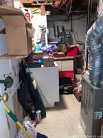 View of toolboxes and assorted tools stacked in a basement utility room.