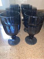 Eight cobalt dusky blue goblets arranged in two rows on a countertop showing front and sides.