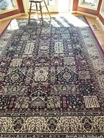 Full view of the wine red and multicolor patterned area rug installed in a well-lit room with hardwood floors.
