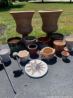 Full collection of plant pots and two large lightweight plastic urns in terracotta color showing various sizes and designs.