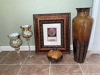 Full set items displayed together on floor showing the tall pottery vase, short vase, framed print, and two candle holders.