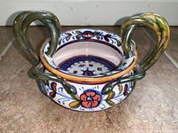 Side angle view showing the bowl's size, shape, and decorative floral pattern with vibrant colors and two large handles.