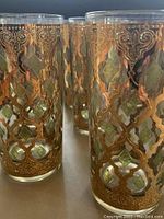 Close-up of one glass showing gold lattice and green diamond shapes in the intricate pattern.