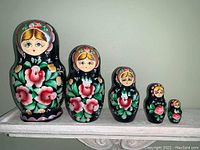 Front view of all five hand painted nesting dolls in a row showing size progression and design details