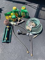 Photo showing all items: garden hose, sprinklers, and Miracle-Gro products arranged on asphalt.