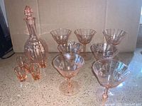 Full set showing decanter with stopper, nine cocktail glasses and five small apertif glasses arranged on countertop