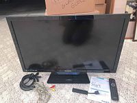 Philips 32-inch TV with remote control, Amazon Fire Stick, cords including power and AV cables shown on carpeted floor.