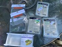 Photo of two plastic soap comb tools on top left, one silicone soap mold underneath, and three blocks of clear soap base on right side on glass table.