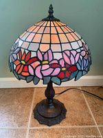 Front view of Tiffany style stained glass lamp showing colorful floral shade and ornate metal base.