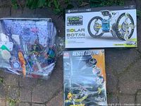 Three STEM kits arranged outdoors: Solar Bot.14, Rescue Copter, and Snap Circuits components in plastic bags.