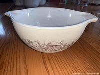 Side view of vintage Pyrex mixing bowl showing forest mushroom design and spout