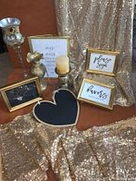 Photo of gold-tone frames with wedding signs, champagne sparkle sequin fabric backdrop and table runners