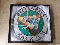 Round wall picture featuring colorful billiards balls arranged in a triangle with text, tied with white ribbon inside a box.