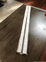 Two white SCHOTTIS window blinds in their original sealed packaging, lying on a dark table.