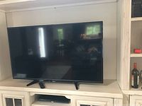 Full front view of the Toshiba 55 inch flat screen television sitting on a white cabinet.