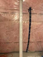 White zebra blind rolled and wrapped in plastic against insulation material background.