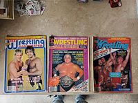 Front covers of three vintage wrestling magazines showing various wrestlers and titles.
