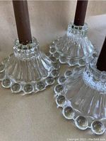 Close-up of the bottom and side detail of the clear glass candle holders showing the ribbed pattern and ring of glass bubbles at the base, with one brown candle inserted.
