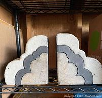 Pair of ceramic bookends showing front with white background and gray cloud design, scalloped pattern.