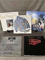 Front side of five LP records for musical theatre featuring Les Miserables, Joseph and the Amazing Technicolor Dreamcoat, Into the Woods, Evita, and Fame.