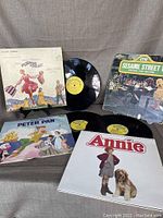 4 vinyl LP records displayed, including Sesame Street 1, Annie, Peter Pan, and The Sound of Music with their sleeves and records laid around