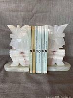 Front view showing 6 Shakespeare paperback books held between two white onyx Aztec-style bookends with pinkish streaks and visible chips/damage.