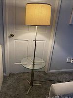 Full view of midcentury floor lamp with beige fabric shade, chrome frame, and integrated glass table.