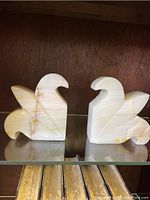 Front view of both onyx fleur de lys bookends showing damage and cracks on left piece.