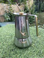 Full side view of the stainless steel Moka coffee maker showing the gold plated handle and knob.