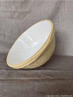 Side angle showing interior white glazed surface and beige/yellow exterior with glossy finish