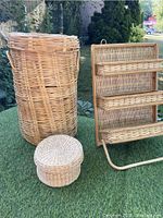 Tall wicker hamper next to shelving unit and two baskets arranged outside on grass.
