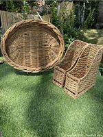 Large round wicker tray and two wicker magazine holders placed on grass outdoors.