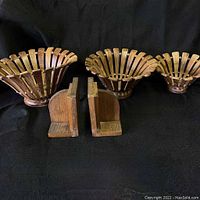 Front view of the three nesting bowls and the pair of wooden Art Deco bookends arranged side by side on a dark surface.