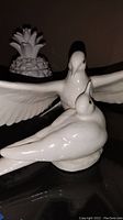 Photo showing the white ceramic doves in front of a clear glass bowl with artistic design, items placed on dark surface.