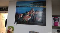 Full view of the large canvas painting showing the ocean and coastal buildings in the landscape.