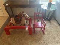 View showing rocking horse and red chair side by side with table and floor visible.
