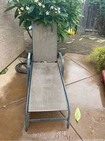 Full view of one outdoor lounger showing the metal frame and mesh fabric seating with some dirt marks
