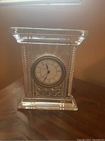Front view of Waterford crystal mantel clock with clear cut glass and round clock face with Roman numerals.
