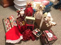 Photo showing assorted Christmas dolls including angel figures and Santa figurines, red tinsel garland, gift bags and decorative holiday items