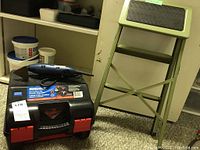 Photo showing Ryobi detail sander on top of Mastercraft circular saw case with red latches on carpeted floor
