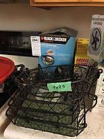 Boxed Black & Decker drip coffee maker along with a black metal wire storage rack marked 11x7.5 inches