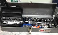 Open metal toolbox showing variety of Craftsman sockets, ratchets, and accessories inside.