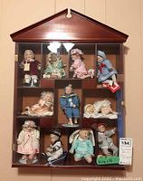 Full view of the wooden doll display case with 11 ceramic dolls inside, showing case dimensions and overall appearance.