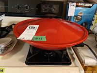 Electric red lid on the wok placed on a stovetop, showing overall condition and size label 15x6.