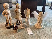 Photo showing all items including two sets of boy and girl figurines, Faberge nativity egg, angel figurine, and angel lamp arranged on carpet