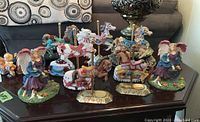 Group of carousel horse and angel figurines displayed on table with couch behind
