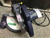 Front and side view of the Mastercraft compound mitre saw showing blade cover and angle adjustment scale with safety label.