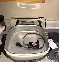 GE electric skillet with temperature control cord coiled inside, rectangular shape, metallic finish