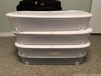 Side view of three stacked Get Sorted under bed storage totes showing white lids and wheels.